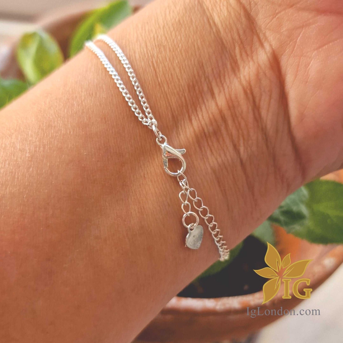 Sterling silver infinity bracelet with double layer curb chain on wrist.